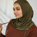 Woman wearing an olive green hijab against a white background