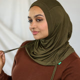 Woman wearing an olive green hijab against a white background