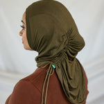 Person wearing an olive green hijab against a white background