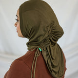 Person wearing an olive green hijab against a white background