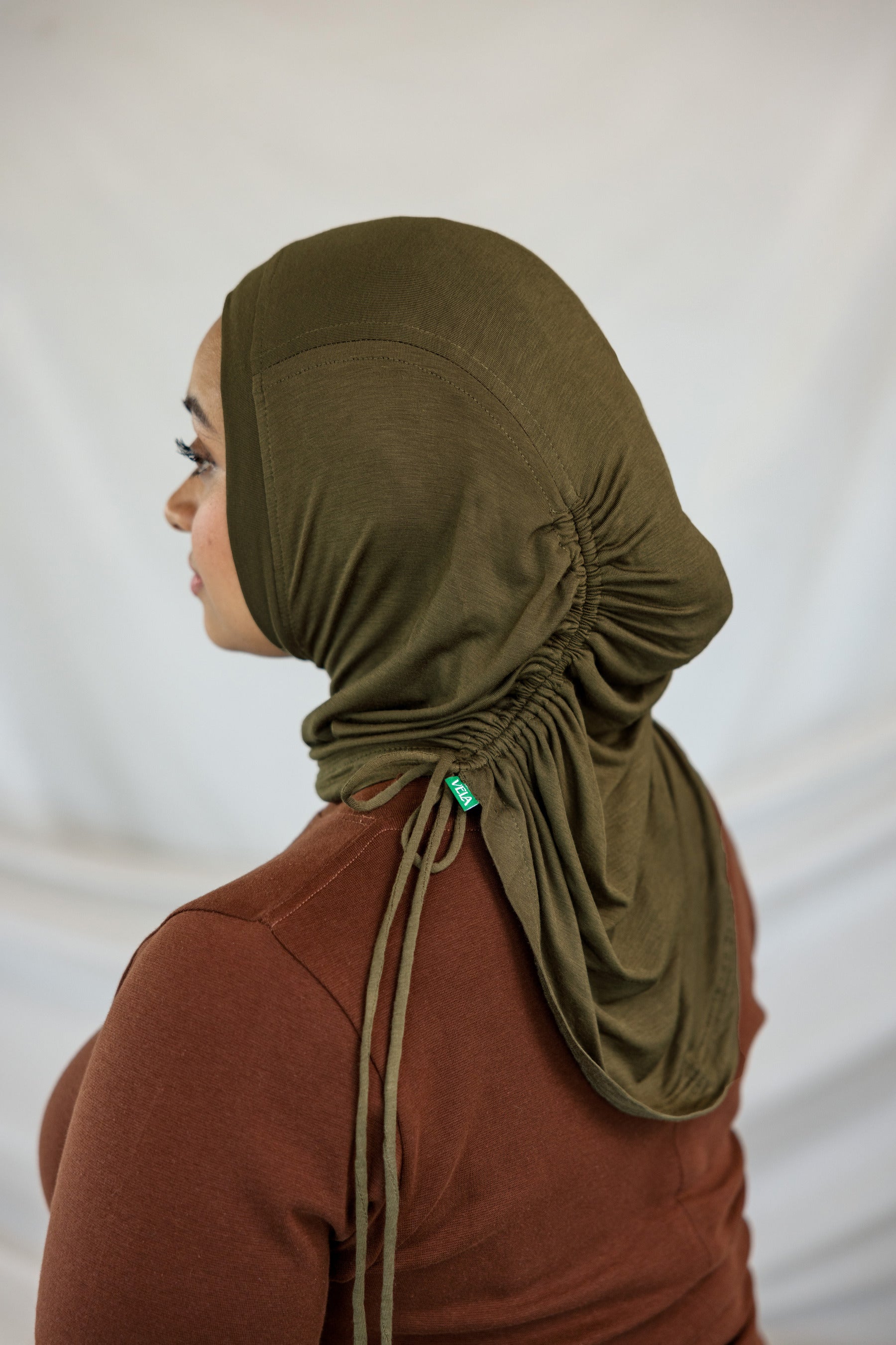 Person wearing an olive green hijab against a white background