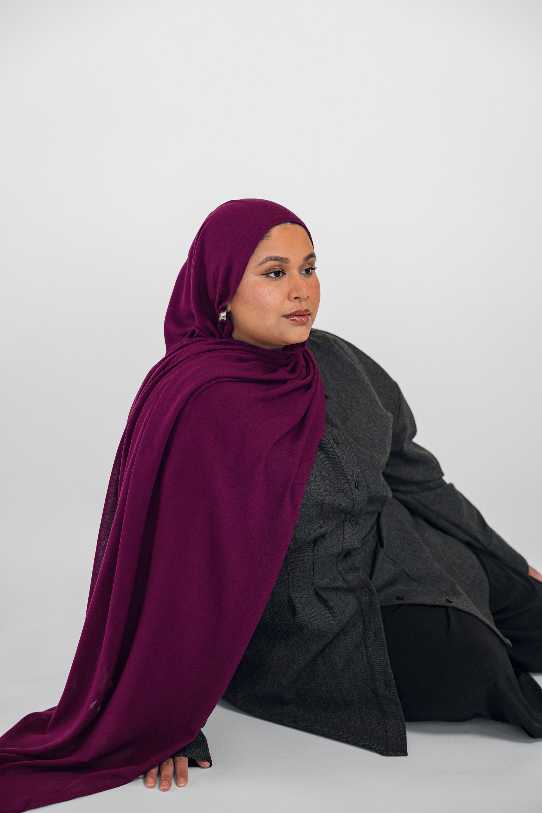 Woman wearing a purple hijab and black outfit on a white background