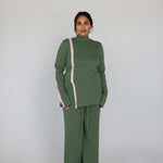 Person wearing a green outfit with a pink stripe on a white background