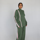Person wearing a green outfit with pink accents on a plain background
