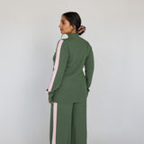 Person wearing a green outfit with pink stripes on the side on a white background