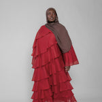Woman wearing a red layered dress and brown hijab on a white background