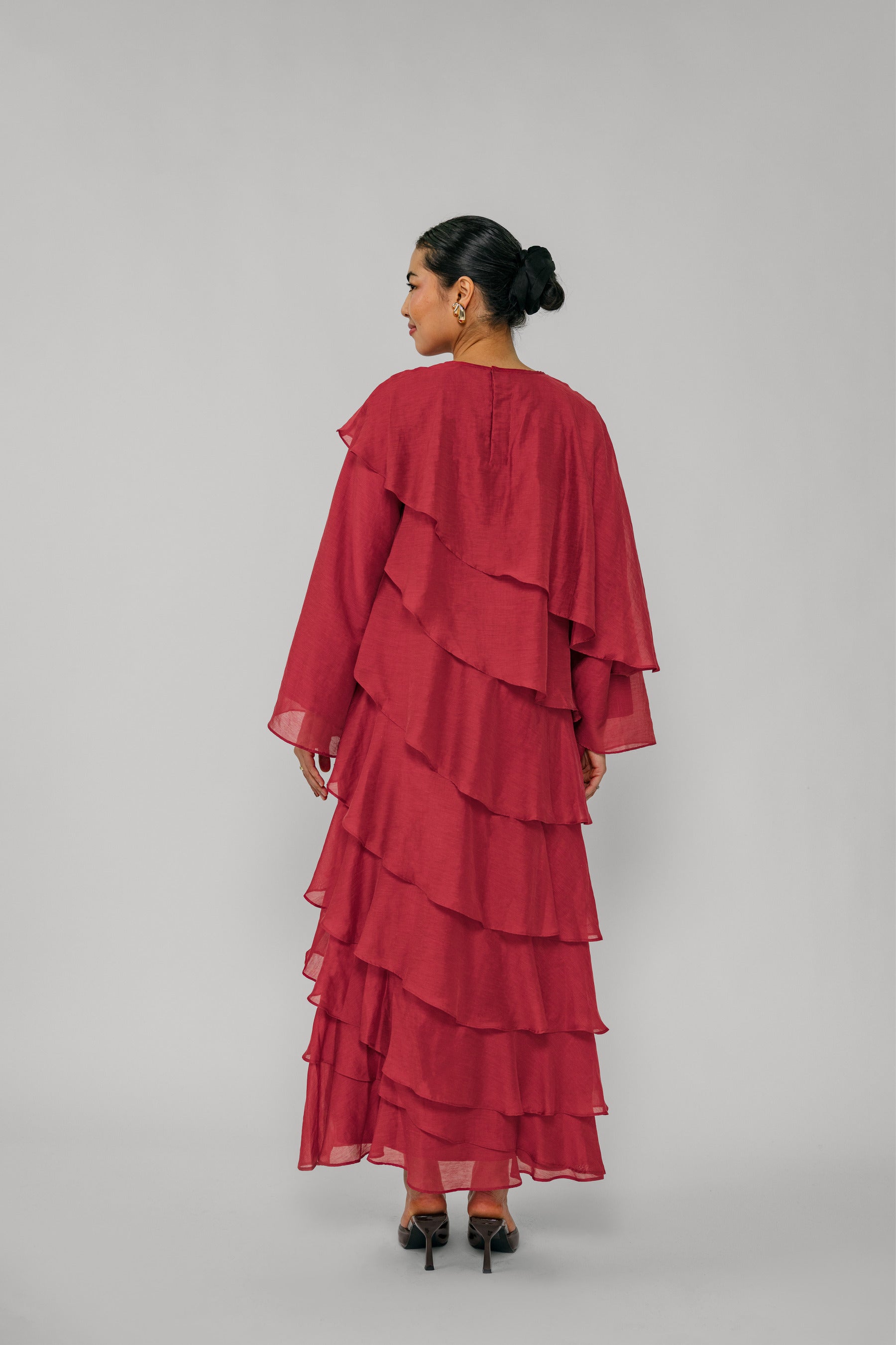 Woman wearing a red layered dress on a gray background