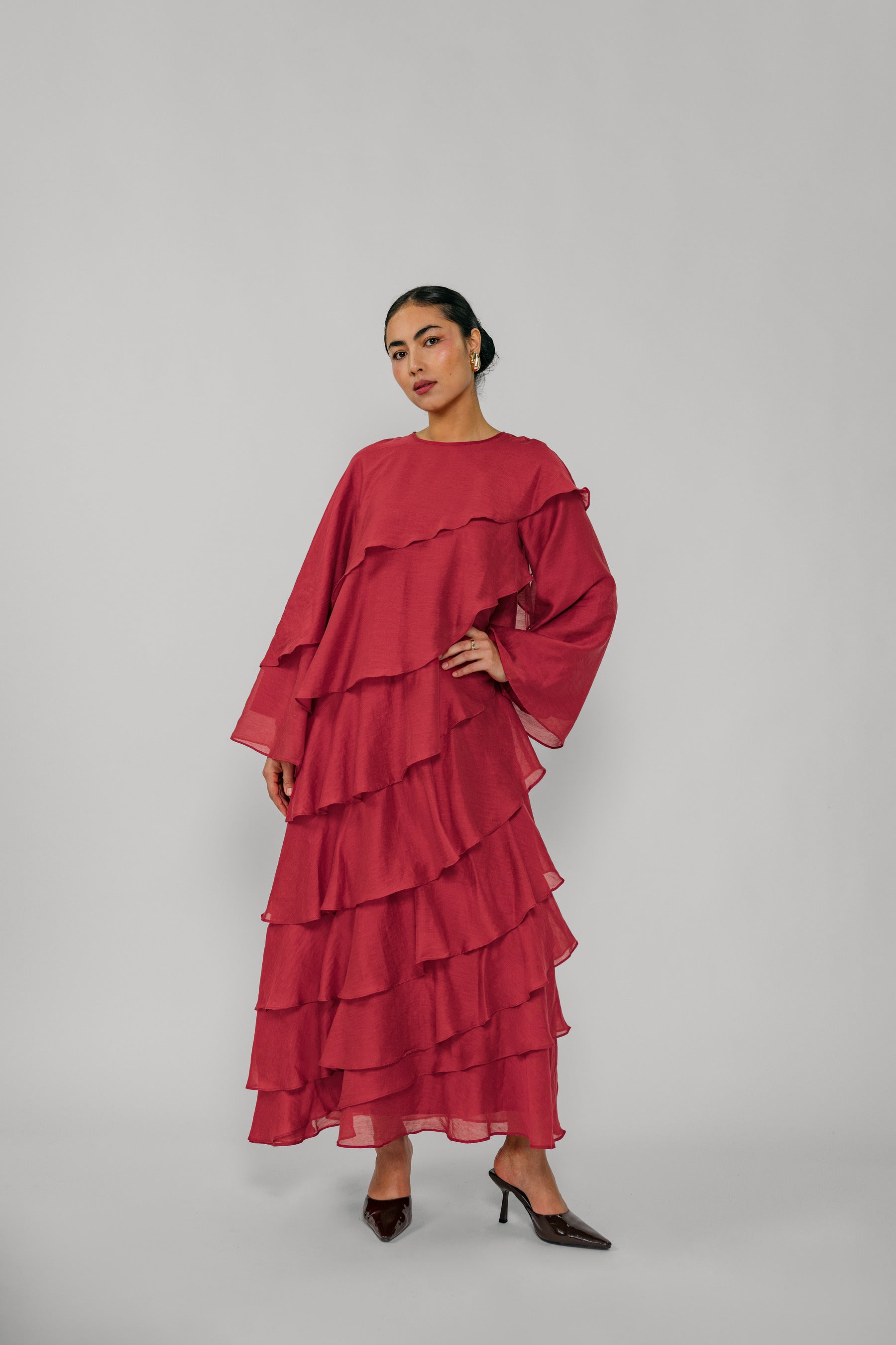 Woman wearing a red layered dress on a gray background