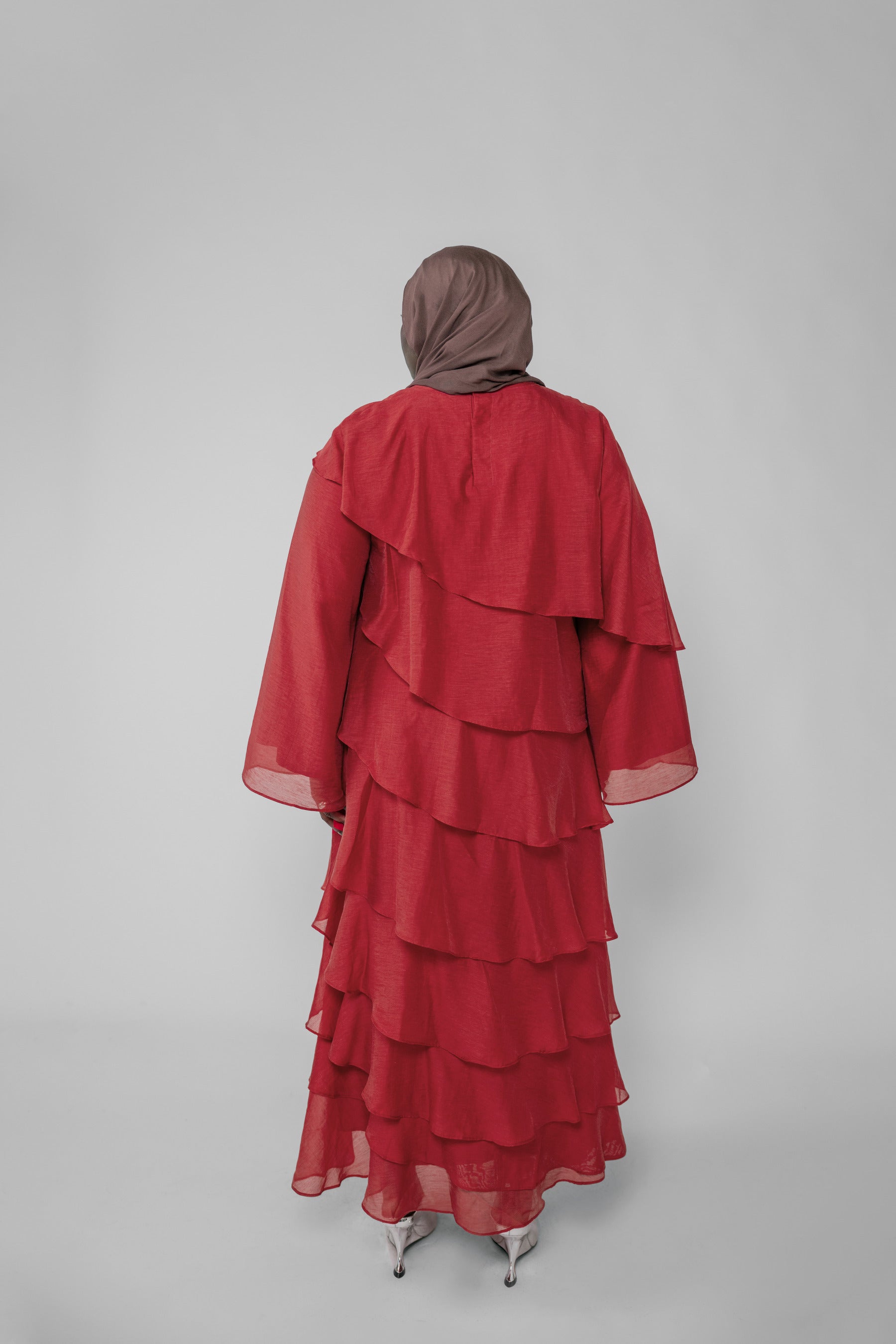Red layered dress with a hijab on a plain background