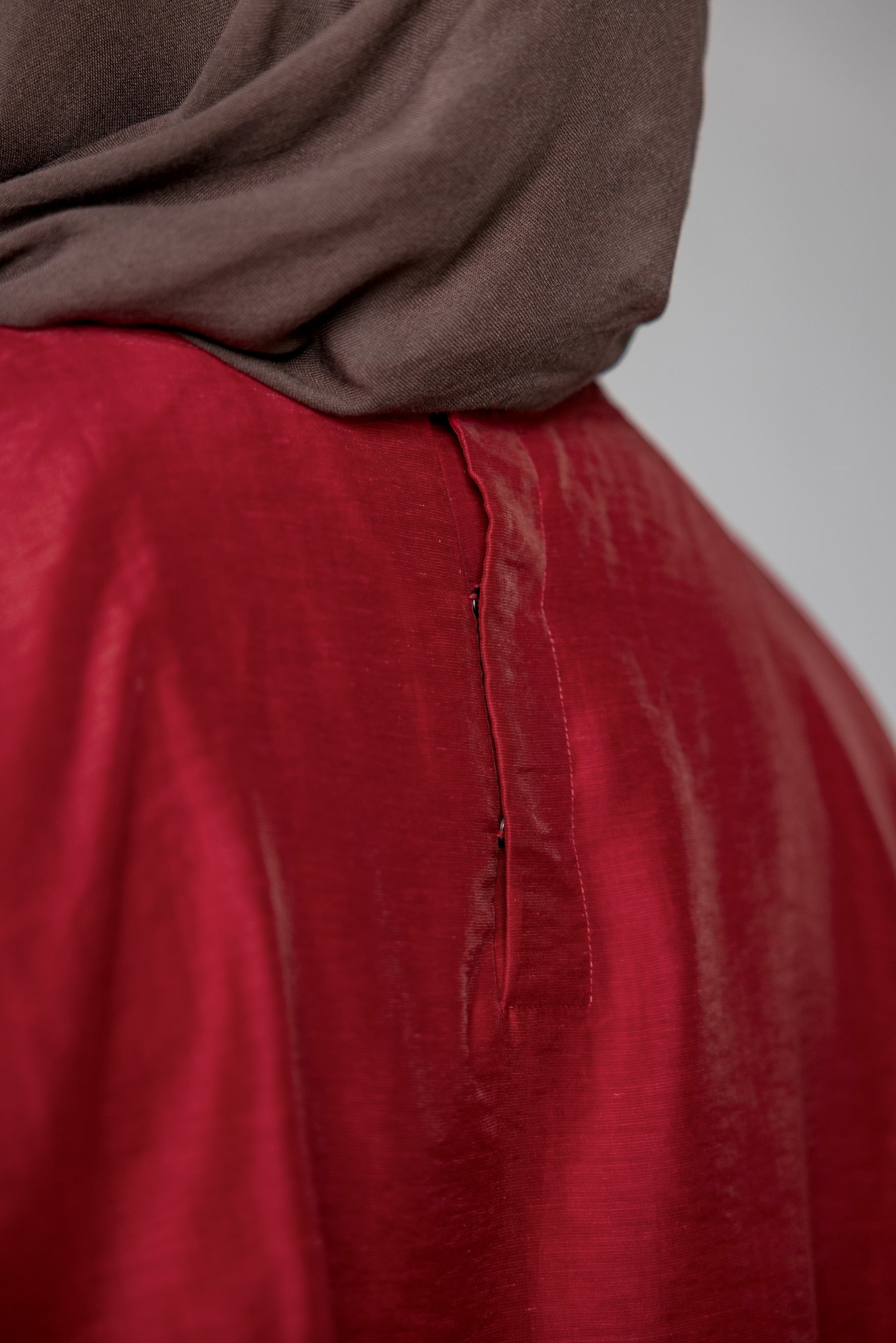 Red garment with a brown hijab on a plain background