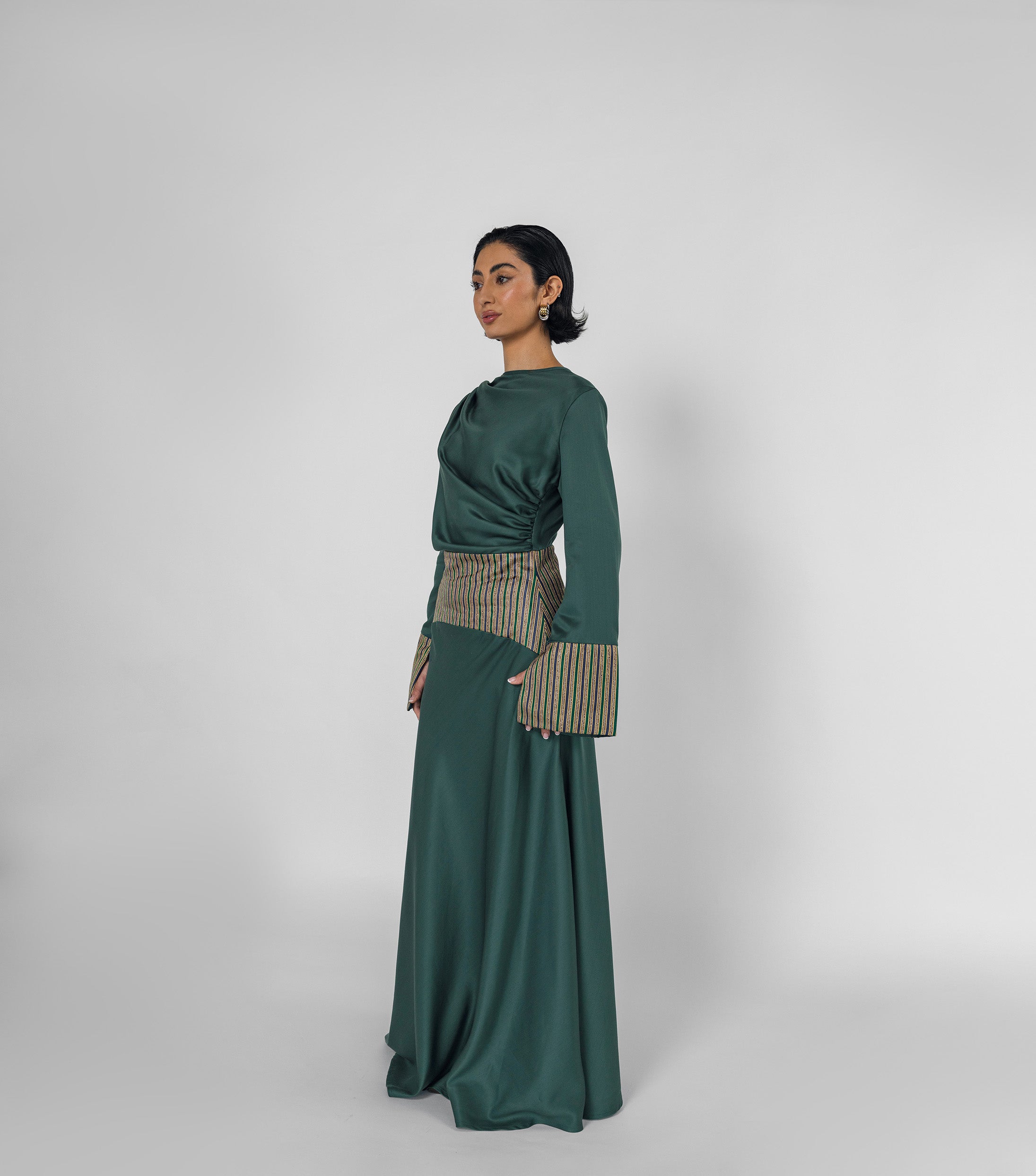 Woman wearing a green dress with patterned accents on a white background