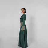 Woman wearing a long green dress with a patterned top on a white background