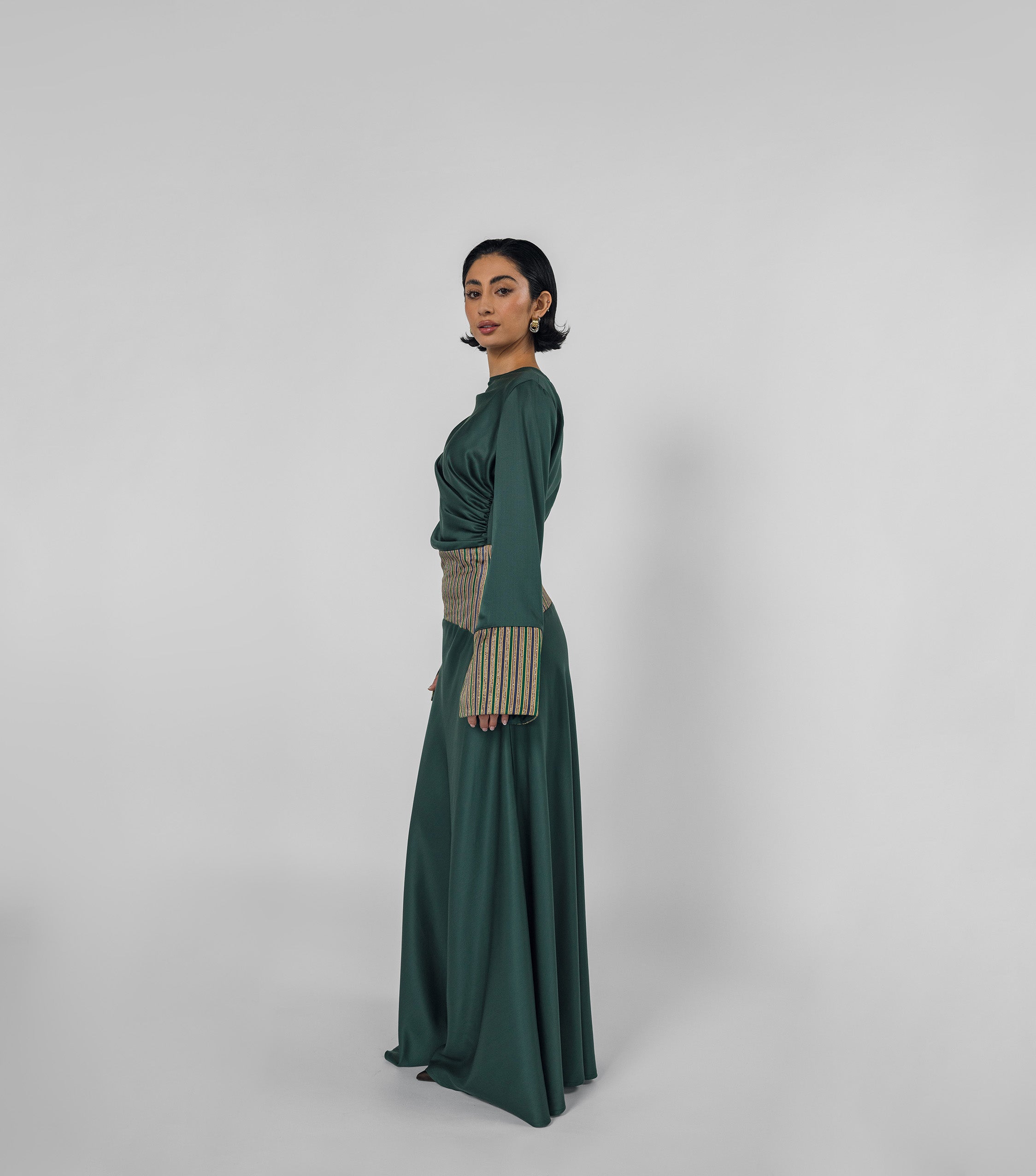 Woman wearing a long green dress with a patterned top on a white background