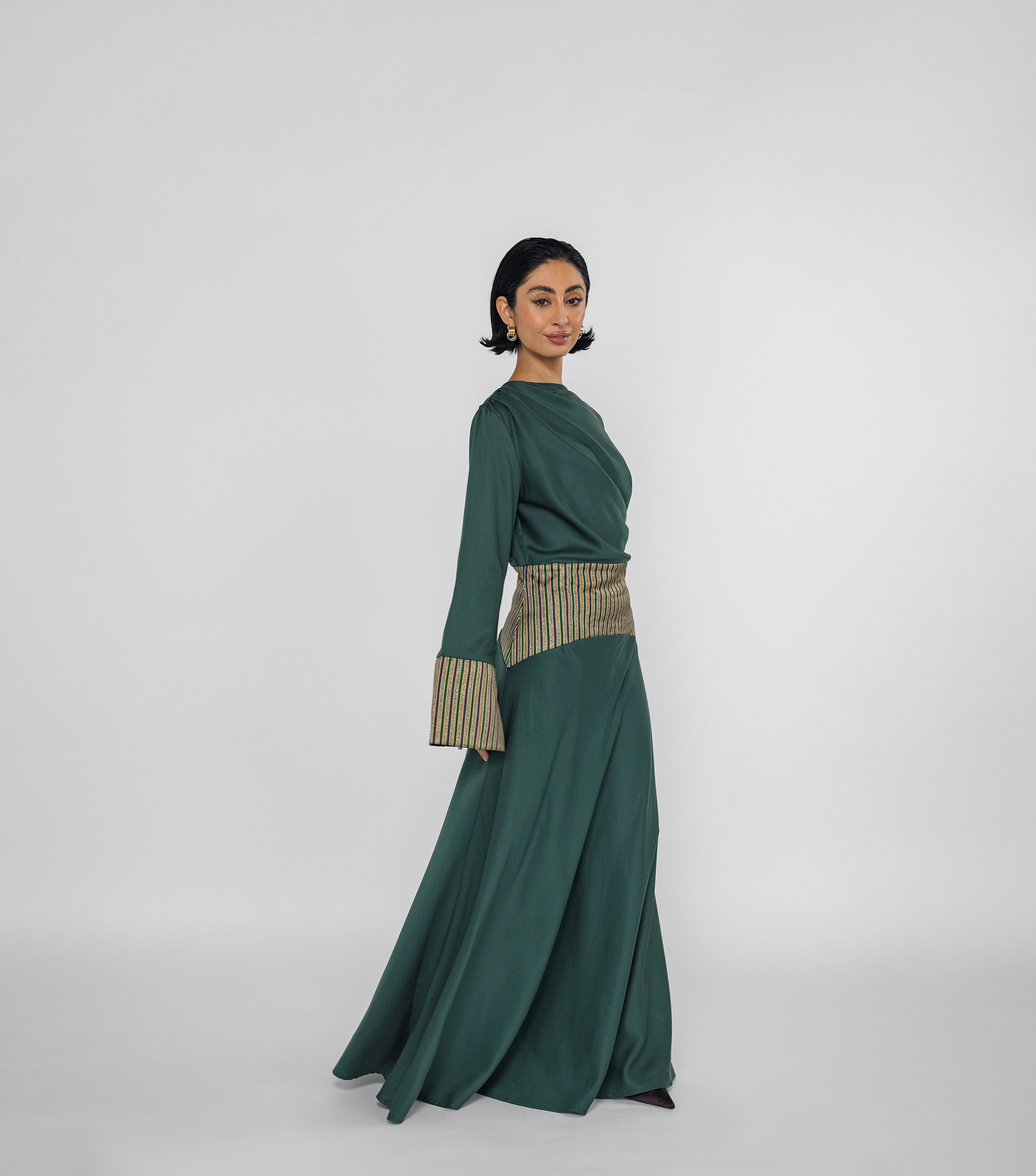 Woman wearing a green dress with a patterned belt on a white background