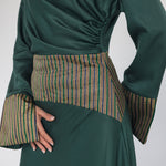 Green dress with patterned cuffs and waistband on a white background