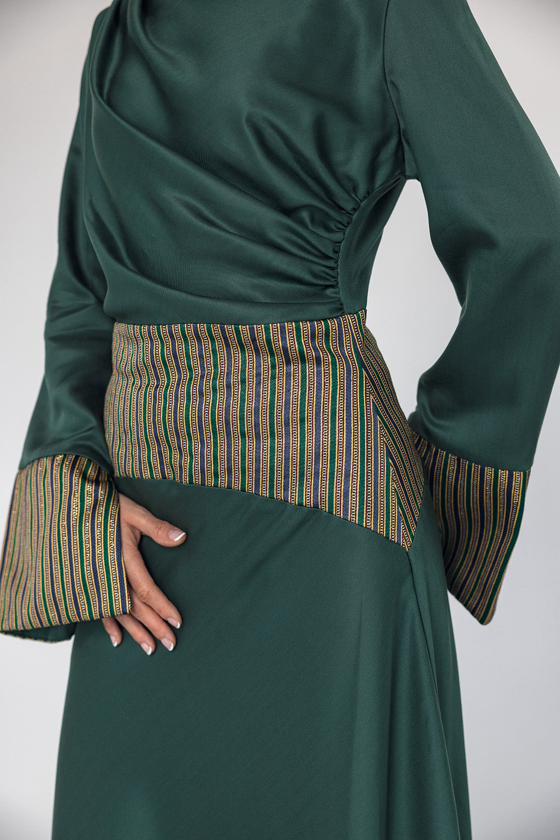 Green dress with patterned cuffs and waistband on a white background