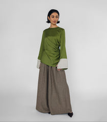 Woman wearing a green top with white cuffs and a brown pants on a white background