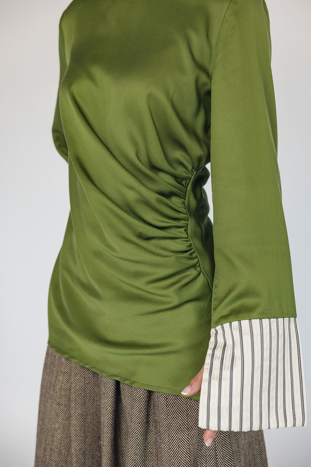 Green long-sleeve top with a ruched design on a plain background