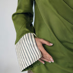 Green garment with striped cuffs on a plain background
