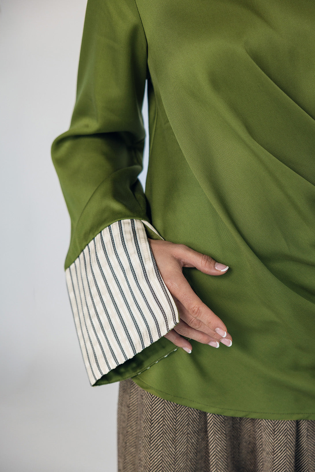 Green garment with striped cuffs on a plain background