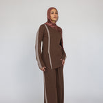 Woman wearing a brown striped matching outfit with a red clay ripple print hijab on a white background