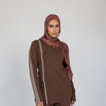 Model styled a brown outfit with a red clay ripple print hijab on a white background