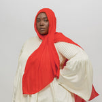 Person wearing a red hijab and white top on a plain background