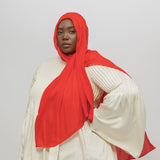 Person wearing a red hijab and white top on a plain background
