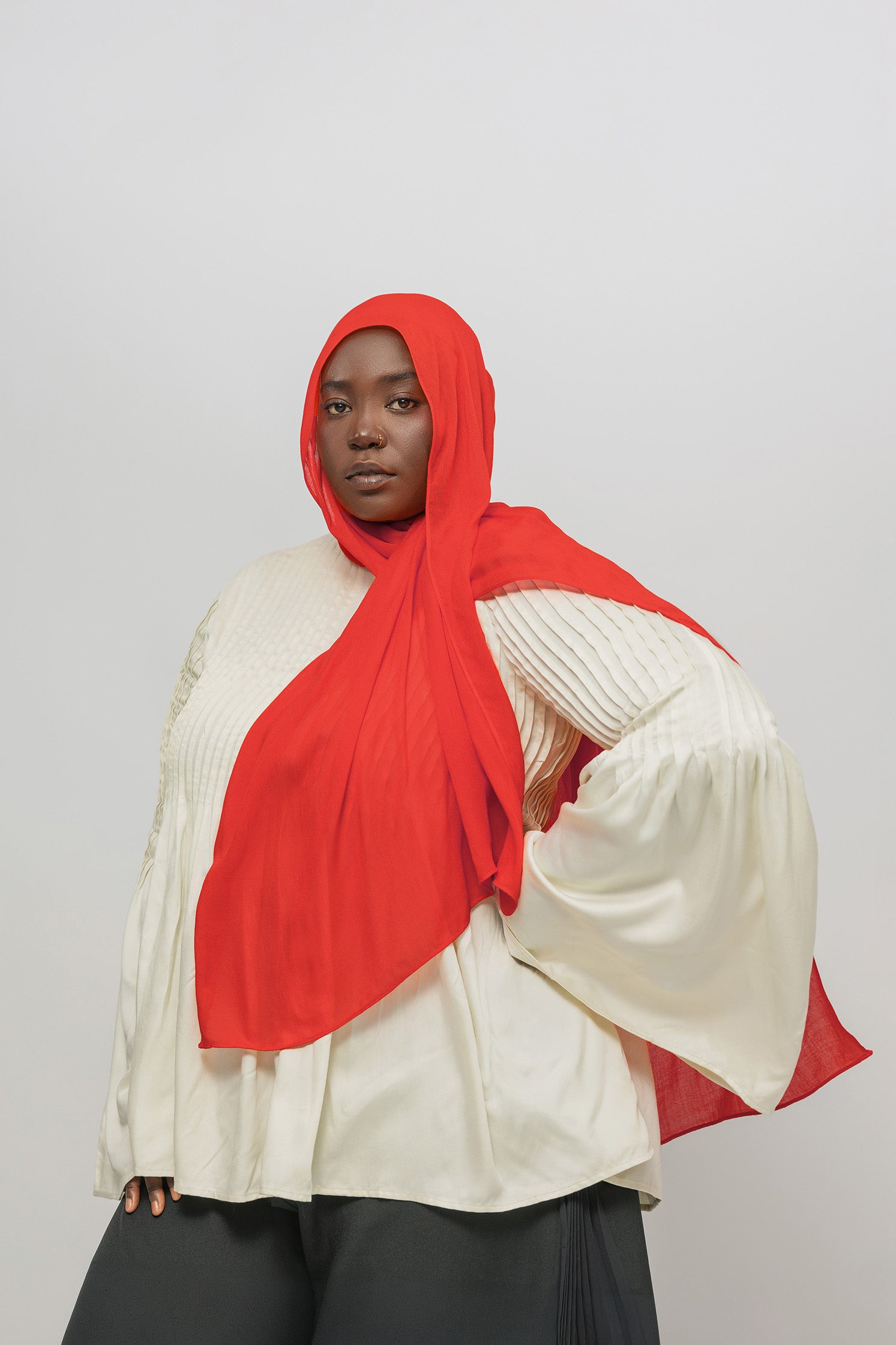 Person wearing a red hijab and white top on a plain background