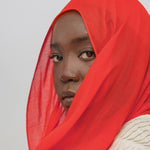 Person wearing a red hijab against a plain background