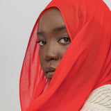 Person wearing a red hijab against a plain background