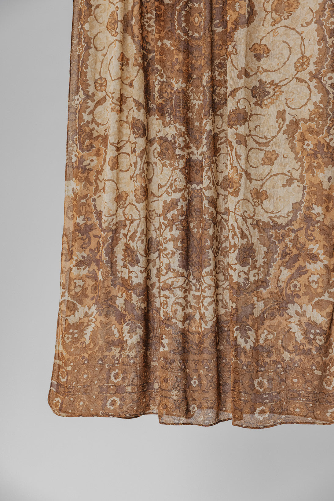 Brown and beige patterned hijab fabric on a plain background