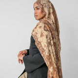 Woman wearing a ivory patterned hijab on a plain background