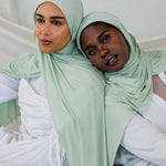  Two models side by side wearing Sage Mist Jersey Lite, showcasing its fresh minty-green tone in both natural and styled wraps.