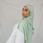 Model wearing Sage Mist Jersey Lite with a soft drape around the shoulders, highlighting its lightweight, wrinkle-resistant finish and its mint color.