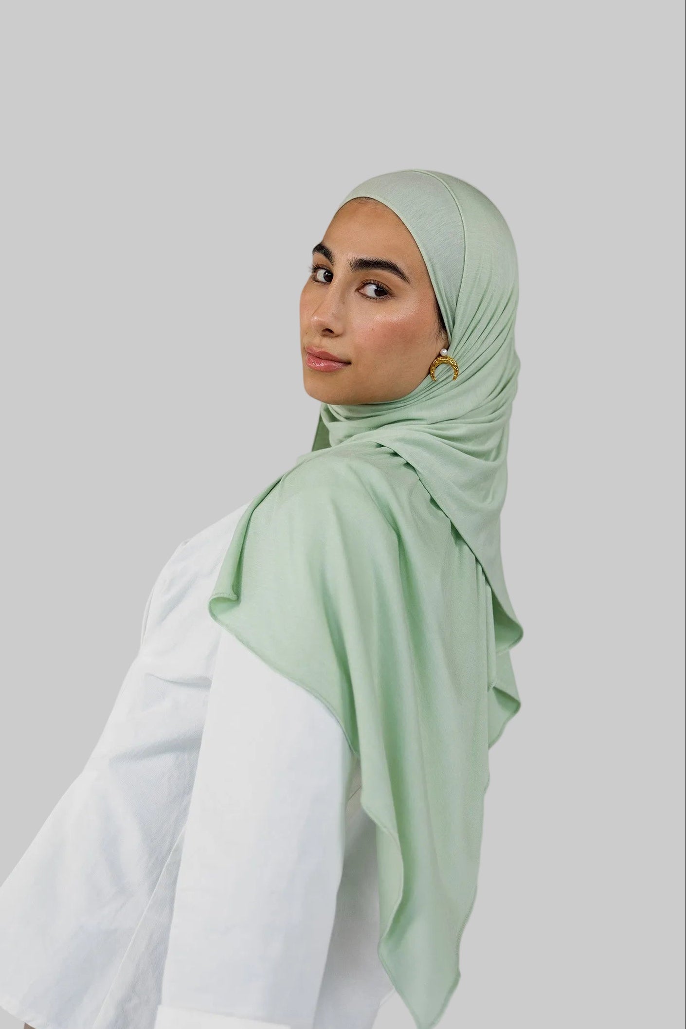 Model wearing Sage Mist Jersey Lite with a soft drape around the shoulders, highlighting its lightweight, wrinkle-resistant finish and its mint color.