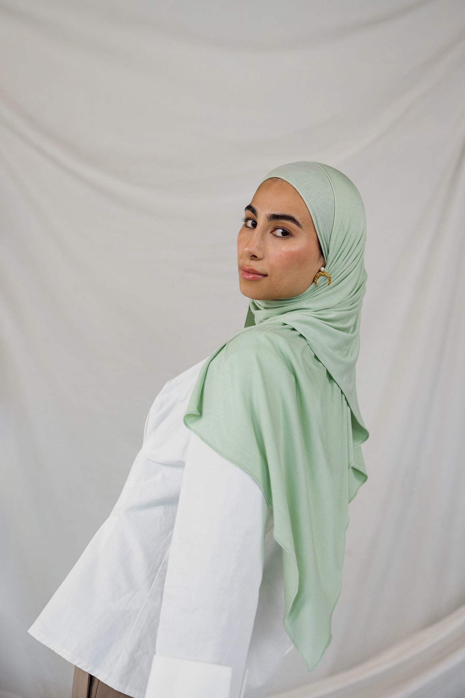 Model wearing Sage Mist Jersey Lite with a soft drape around the shoulders, highlighting its lightweight, wrinkle-resistant finish and its mint color.