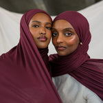 Two models side by side wearing Antique Cherry Jersey Lite, contrasting its tone shifting burgundy shade under different light.
