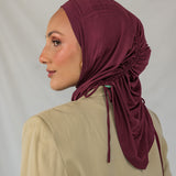 Model wearing a maroon ruched hijab against a plain background. 
