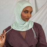 Model wearing Sage Mist Ruching Lite with light ruching around the face, emphasizing airy drape.
