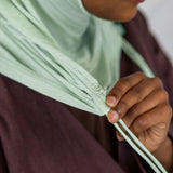Close-up view of the Sage Mist Ruching Lite hijab depicting the model using the ruching strings. 
