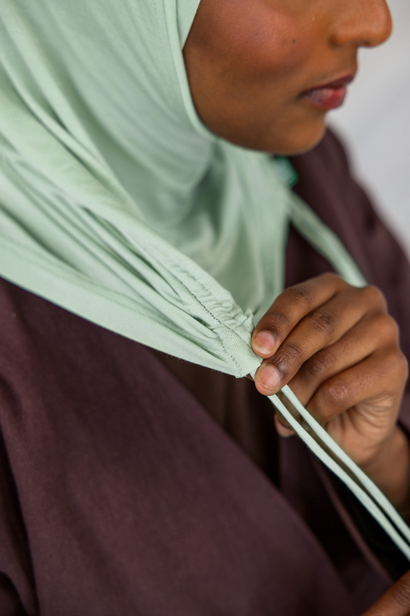 Close-up view of the Sage Mist Ruching Lite hijab depicting the model using the ruching strings. 