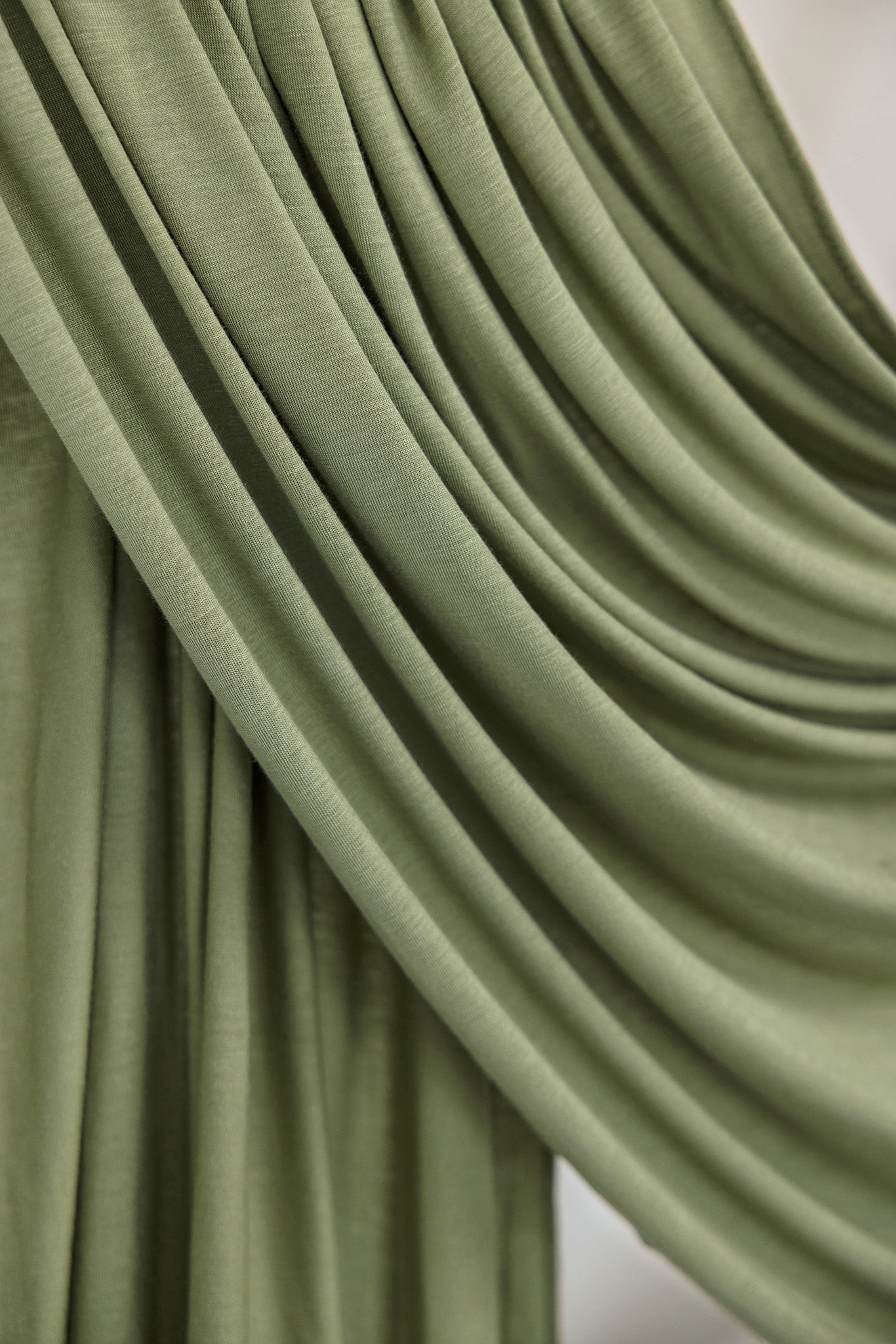 Palm Desert Jersey Lite fabric draped in front of white backdrop, revealing olive tone and airy jersey weave.