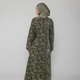 Woman wearing a green jacquard patterned abaya on a gray background