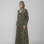 Woman wearing a green jacquard patterned abaya on a gray background