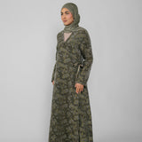 Woman wearing a green jacquard patterned abaya on a gray background