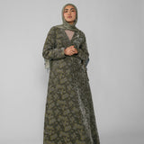 Woman wearing a green jacquard patterned abaya on a gray background