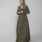 Woman wearing a green jacquard patterned abaya on a gray background