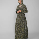 Woman wearing a green jacquard patterned abaya on a gray background