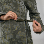 Person wearing a green floral patterned abaya against a plain background